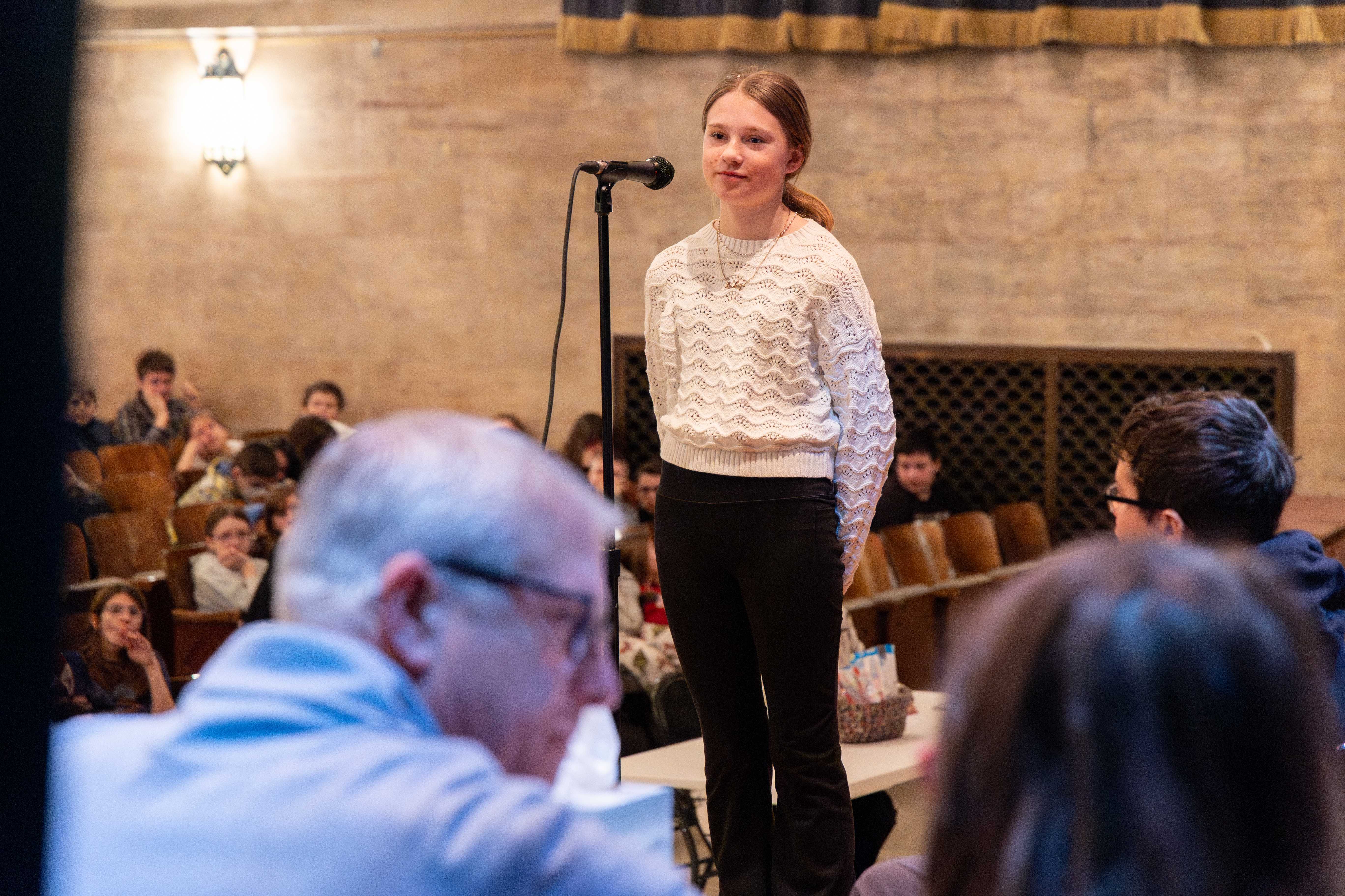 A student smiles as she waits for the next word at the microphone